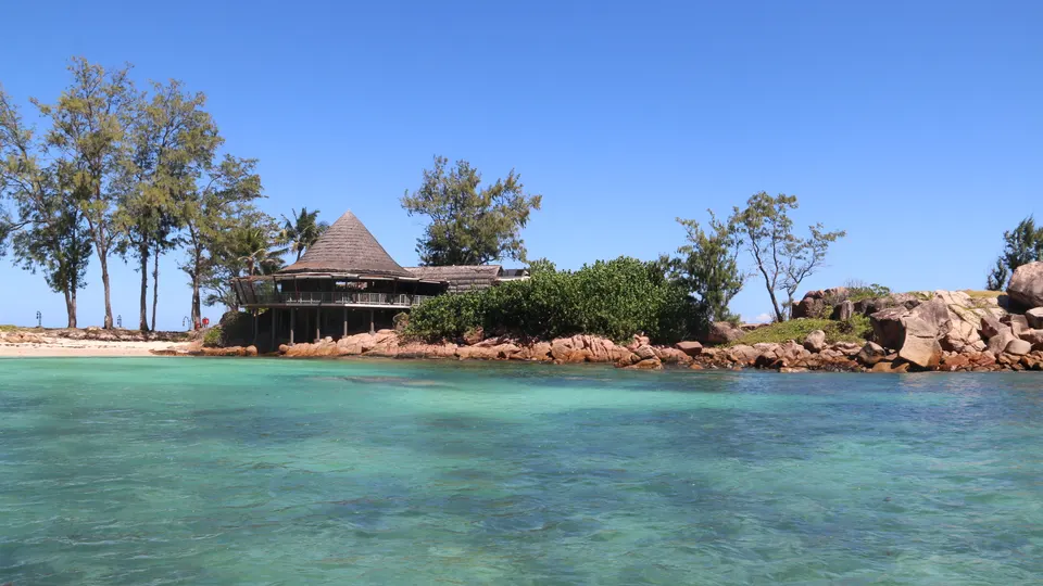 A thatched pavilion set among granite boulders above the water